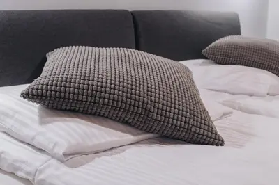a bed with a brown pillow on top of it at M2 Main Square Studio in Kraków