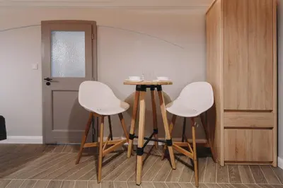 a room with three white chairs and a table at M2 Main Square Studio in Kraków