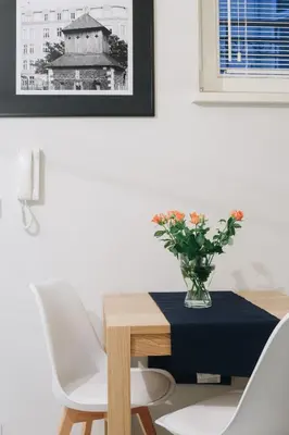 a dining room table with two chairs and a vase of flowers at M6 Main Square Stylish One Bedroom in Kraków
