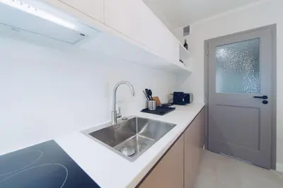 a white kitchen with a sink and a door at M7 Main Square with Free Parking Friends Escape in Kraków
