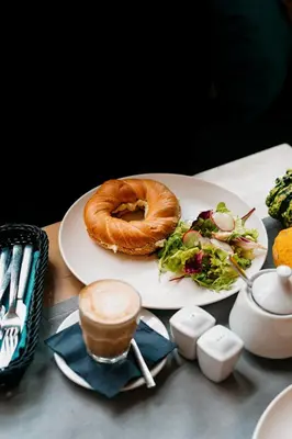 a plate with a bagel and salad on a table at Oak Tree Old Town Apartments in Kraków