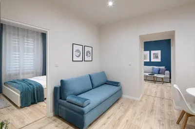 a living room with a blue couch and a bed at Native Apartments Starowiślna 33A Deluxe in Kraków