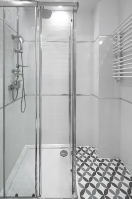 a shower with a glass door and a black and white floor at Native Apartments Starowiślna 33A Deluxe in Kraków