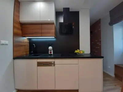 a kitchen with white cabinets and a black counter top at Cracowapart Ignacio B in Kraków