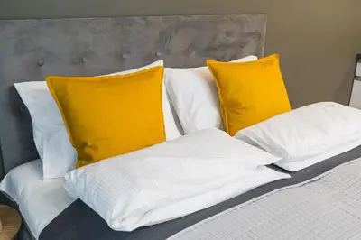 a bed with white sheets and yellow pillows at Sarah Apartments Old Town in Kraków