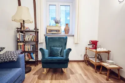 a living room with a blue chair and a couch at 29 Avenue Apartments in Kraków