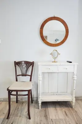 a chair next to a white desk and a mirror at 29 Avenue Apartments in Kraków
