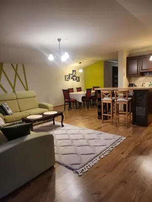 a living room and kitchen with a couch and a table at Apartament Kleopatra in Limanowa