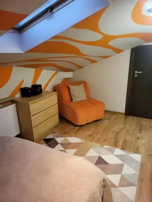 an attic room with a bed and a chair at Apartament Kleopatra in Limanowa