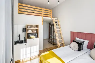 a bedroom with a loft bed and a kitchen at Horizon Park Aparthotel in Kraków