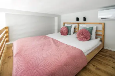 a bedroom with a bed with a pink blanket and pillows at Horizon Park Aparthotel in Kraków