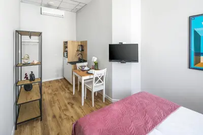 a bedroom with a bed and a desk and a tv at Horizon Park Aparthotel in Kraków