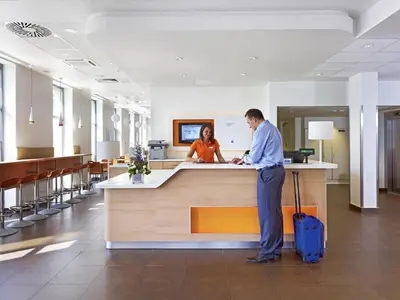 a waiting room with orange chairs and a table at ibis budget Krakow Stare Miasto in Kraków