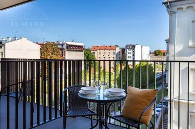 a table and chairs on a balcony with a view at Fragola Apartments Rajska 3 - modern studios, park in Kraków