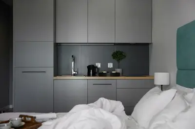 a kitchen with gray cabinets and a bed in a room at Fragola Apartments Rajska 3 - modern studios, park in Kraków