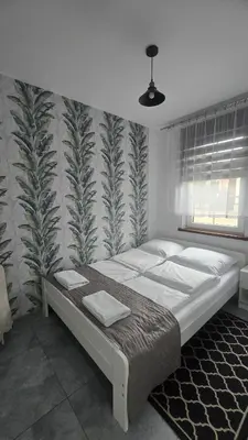 a bedroom with a large bed with a tropical wallpaper at Country House - apartamenty blisko Energylandii in Spytkowice