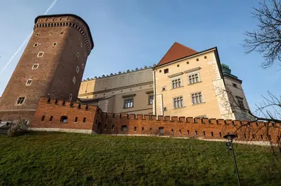 a large castle with a brick wall next to a building at 3D Wawel Apartament in Kraków