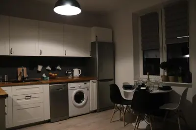 a kitchen with a washing machine and a table with chairs at Szeroka View Apartment in Kraków