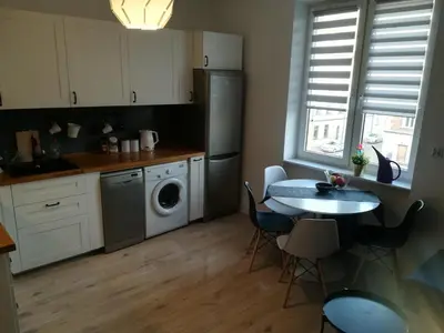 a kitchen with a table and a sink and a dishwasher at Szeroka View Apartment in Kraków