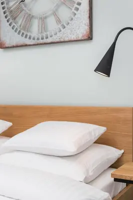 a bed with white pillows and a black lamp at City of the Kings-Bijou Apartment in Kraków