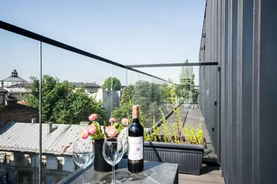 a bottle of wine and glasses on a table on a balcony at Central balcony apartment - Window on Cracow in Kraków