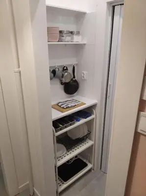 a small kitchen with white shelves and a refrigerator at Lovely Madly Apartment in Kraków
