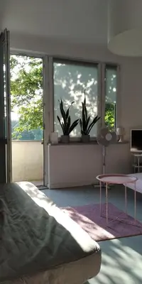a bedroom with a bed and a table and windows at Lovely Madly Apartment in Kraków