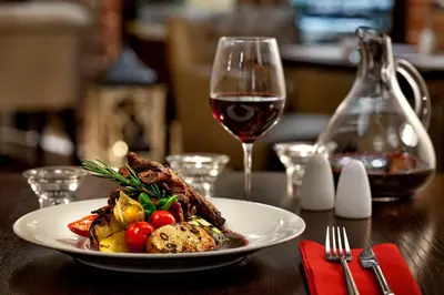 a plate of food and a glass of wine on a table at Metropolitan Boutique Hotel in Kraków