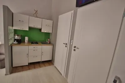 a small kitchen with white cabinets and a green wall at Rainbow Apartments 2 in Kraków
