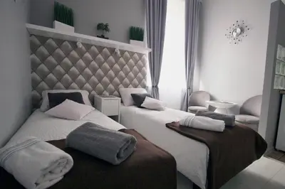 a hotel room with two beds and a chair at Rainbow Apartments 2 in Kraków