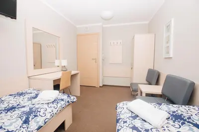 a room with two beds and a desk and a mirror at Strumyk in Kraków