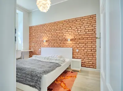 a bedroom with a brick wall and a bed at 3D WYGODA Apartamenty in Kraków