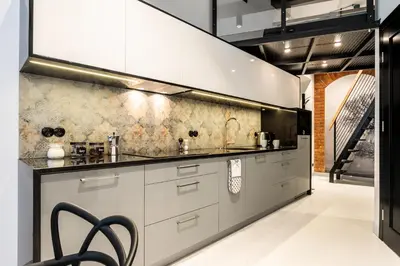 a kitchen with white cabinets and a wall at 3D WYGODA Apartamenty in Kraków