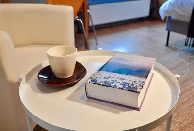 a table with a book and a cup on it at Tresor Barska Apartments 2.0 in Kraków