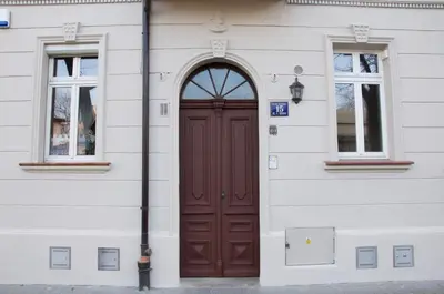 a brown door on a white building with two windows at Tresor Barska Apartments 2.0 in Kraków