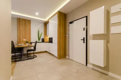 a hallway with a door and a table and a kitchen at Krakowiak Apartments in Kraków