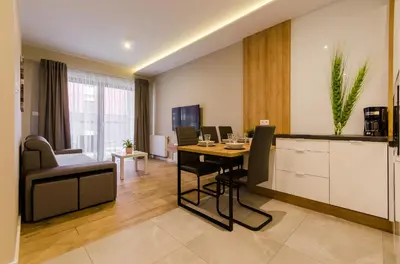 a living room with a table and a kitchen at Krakowiak Apartments in Kraków