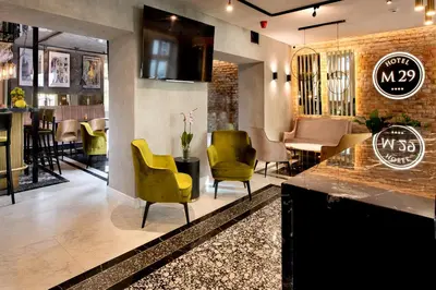 a restaurant with yellow chairs and a bar at Hotel M29 in Kraków