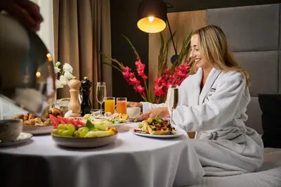 a woman sitting at a table with plates of food at Hotel M29 in Kraków