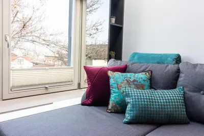 a gray couch with colorful pillows in front of a window at Apartment NEARTO Old Town Miodowa Parking in Kraków