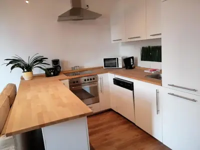 a kitchen with white cabinets and a wooden counter top at Apartament Galicja in Chrzanów