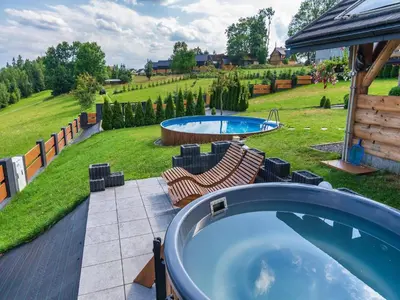 a hot tub on a patio with a yard at Villa in Nowy Targ with Mountain Views & Pool in Nowy Targ
