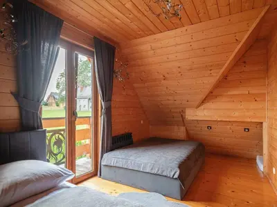 a bedroom with two beds in a wooden room at Villa in Nowy Targ with Mountain Views & Pool in Nowy Targ