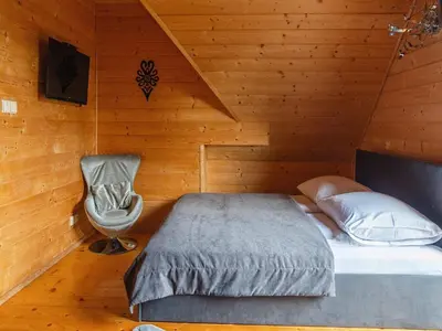 a bedroom with a bed and a chair at Villa in Nowy Targ with Mountain Views & Pool in Nowy Targ