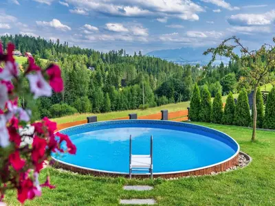 a swimming pool in a field with a chair at Villa in Nowy Targ with Mountain Views & Pool in Nowy Targ