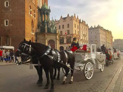a couple of horses pulling a carriage down a street at Studio Appartment in Old Town Krakow in Kraków