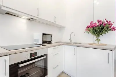 a kitchen with white cabinets and a vase of flowers at Studio Appartment in Old Town Krakow in Kraków