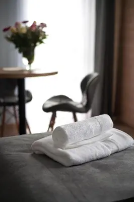 two towels on a bed with a table and a chair at Willa-Wita in Kalwaria Zebrzydowska
