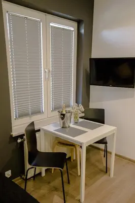 a white table and chairs in a room with windows at ULMA studio in Wieliczka