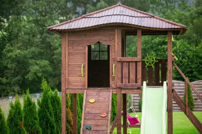 a wooden play house with a slide in a yard at Zielona willa in Rabka